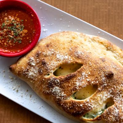 Freshly baked calzone sprinkled with Parmesan cheese served with marinara sauce.