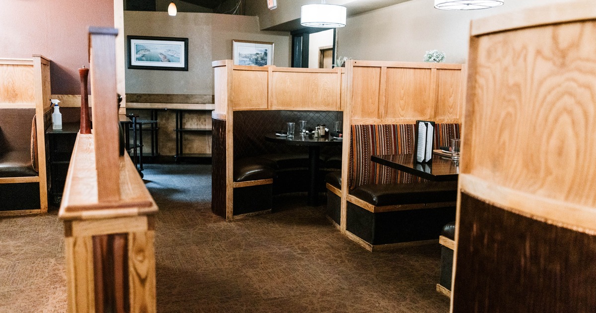 Interior view of a cozy restaurant featuring wooden booths with dark leather seating