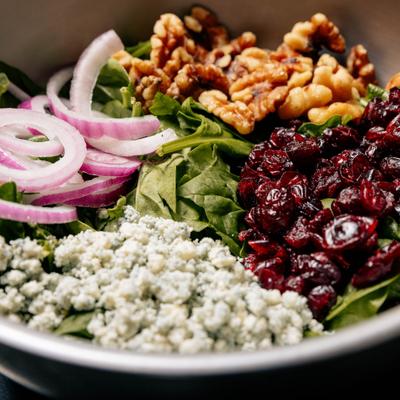 Spinach salad with crumbled blue cheese, dried cranberries, walnuts, and red onion.
