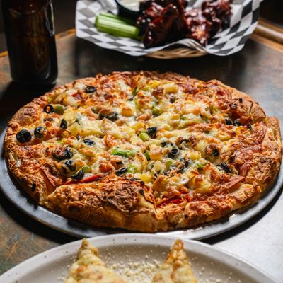 Vegetable pizza on metal tray with melted cheese topping.