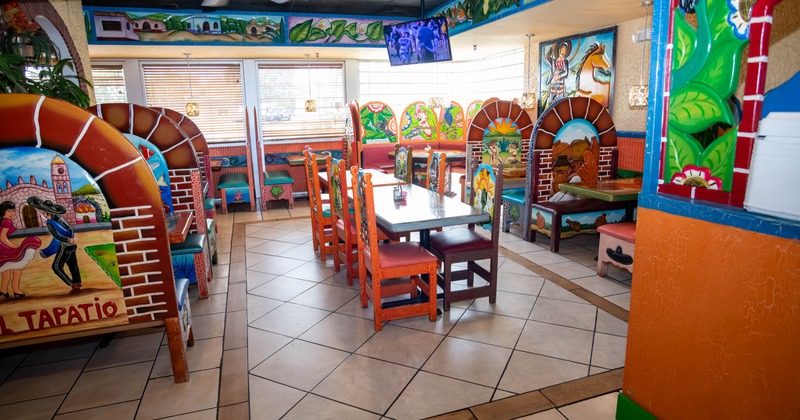 Interior of a colorful restaurant with painted wooden booths and chairs