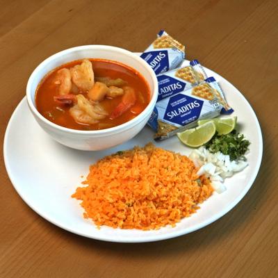 Shrimp soup served with rice, crackers, onion, cilantro, and lime.