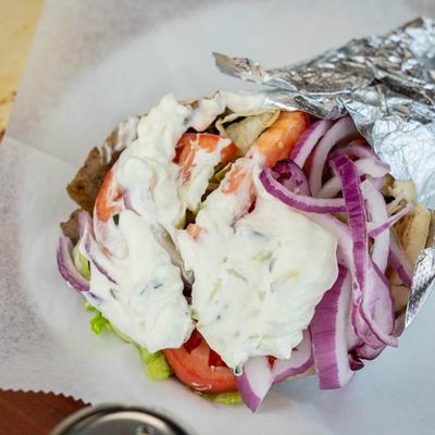 Gyro with meat, tomatoes, onions, and tzatziki sauce, close-up.