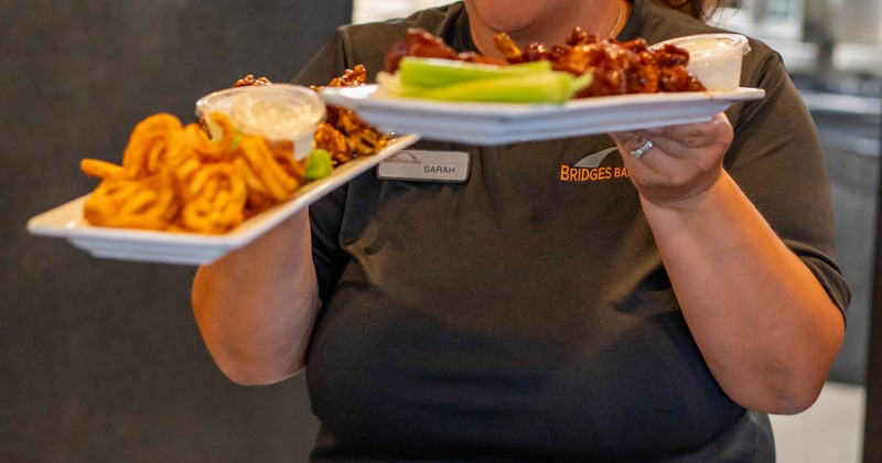 A waitperson carrying plates with meal order