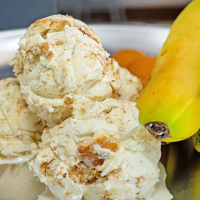 Banana Pudding Ice Cream on metal tray beside ripe bananas, close up.