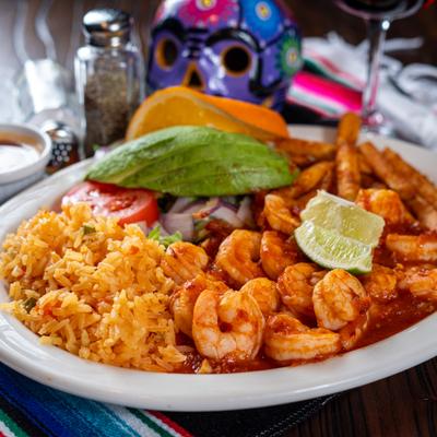 Shrimp in spicy tomato sauce served with rice, salad, and avocado slices.
