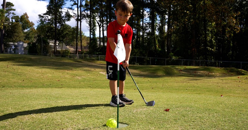A kid with a golf club on the field