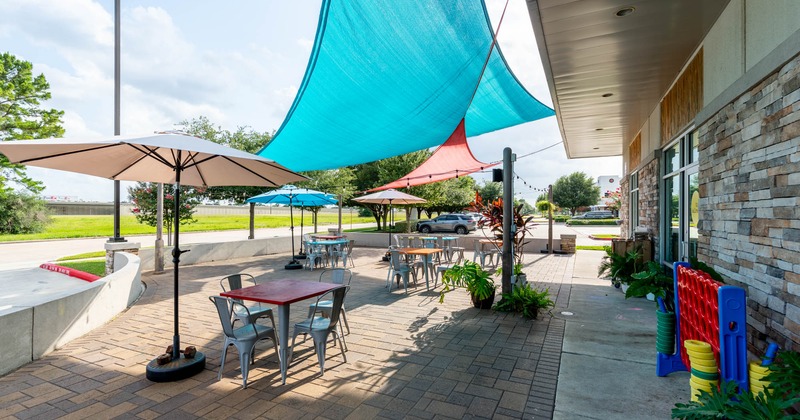 Exterior, partially covered area, tables and chairs under parasols, stone pavement