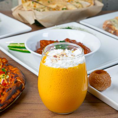 Mango Lassi drink with assorted food plates.