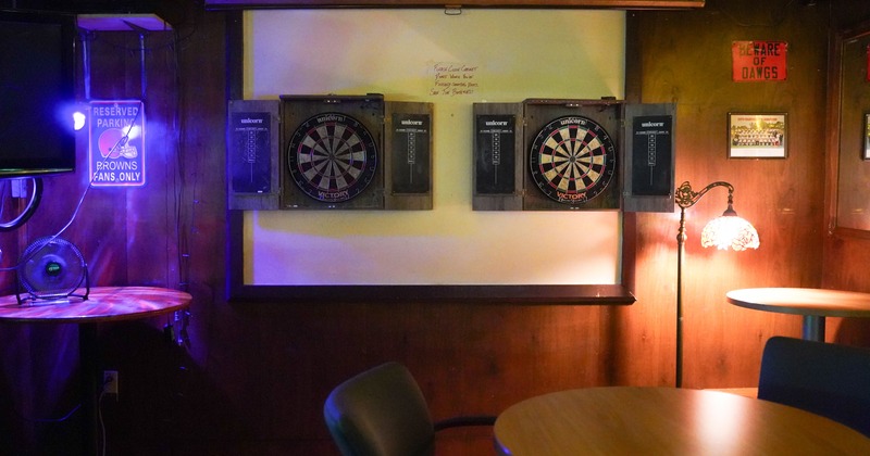 Tables, chairs, darts targets on the wall behind