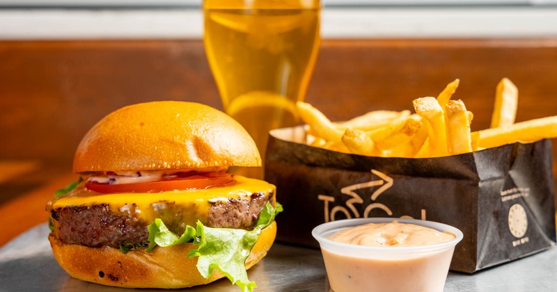Black label burger with fries, dipping sauce, and a beer
