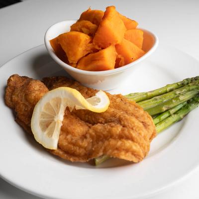 Fried fish fillet with lemon, asparagus, and sweet potatoes.