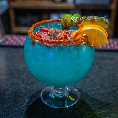 Fish ball cocktail with spicy rim, and lime, orange, and pineapple garnish.