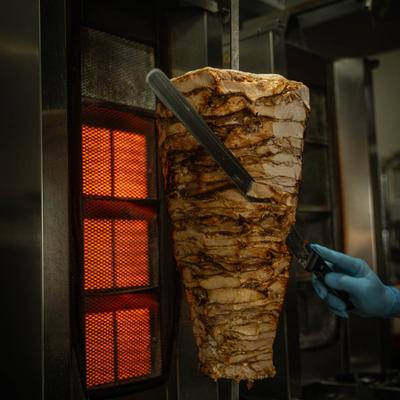 Shawarma being cooked on a vertical rotisserie.
