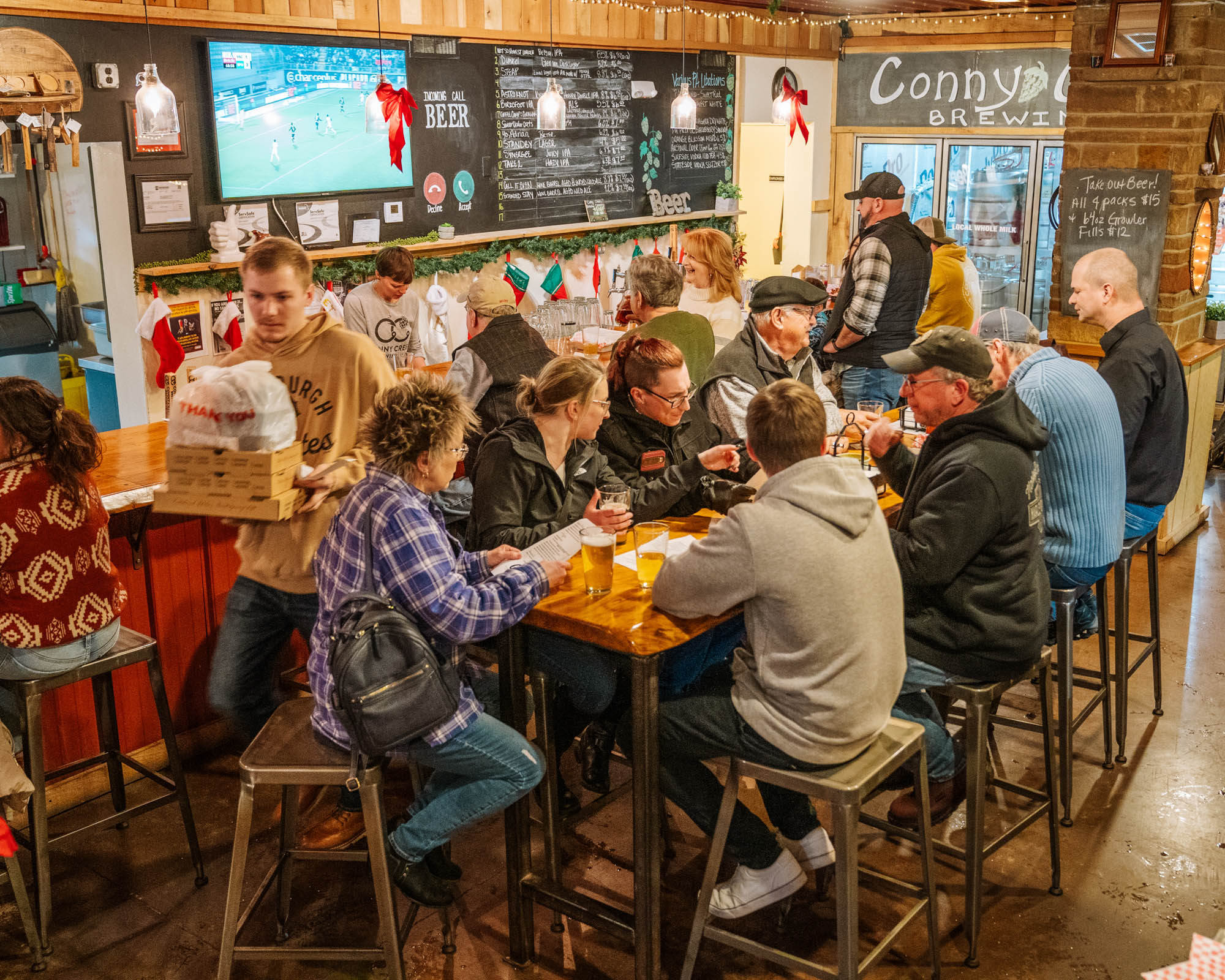 Crowded interior with high-top wooden tables and industrial-style metal stools