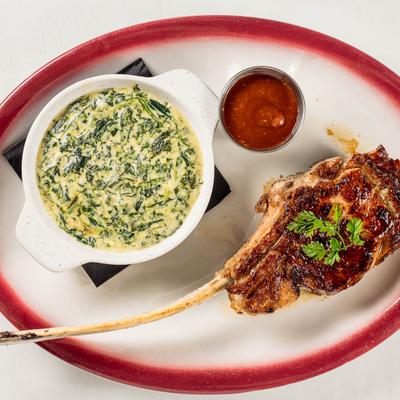 Veal chop with herbs served with a spinach dip.