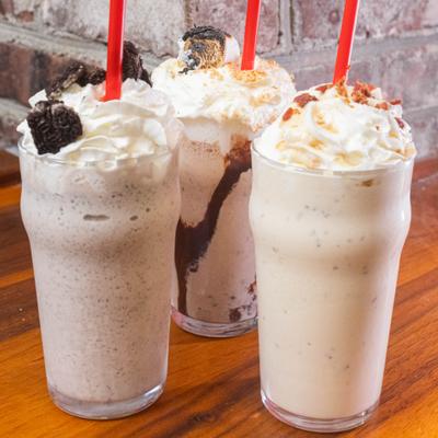 Various milkshakes topped with whipped cream.