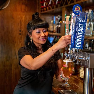 A bartender pours beer into a glass from a draft tap.