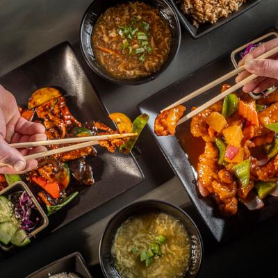 People sharing dishes with chopsticks over table.