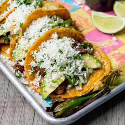 Tacos topped with cheese and greens.