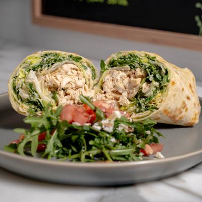 Grilled Chicken Caesar Wrap sliced in hald and served with a side salad.