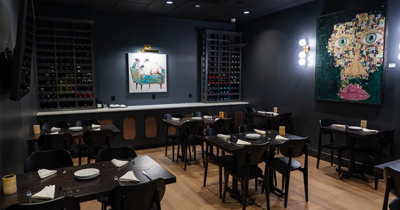 Modern dining area with tables, chairs, wine racks and eclectic artwork on the walls