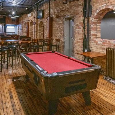 A pool table in the rustic interior setting.