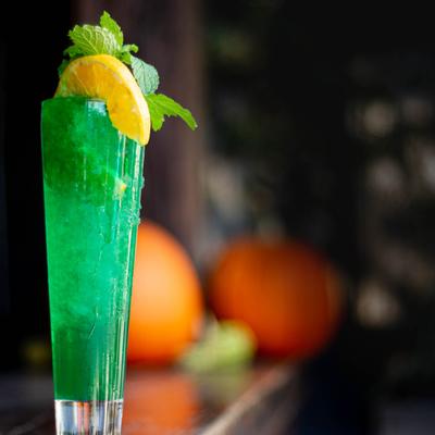 A refreshing green drink garnished with a slice of lemon and fresh mint leaves.