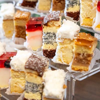 Assorted layered cake squares on a clear stand.