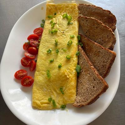 Omelette with grape tomatoes, accompanied with slices of bread.