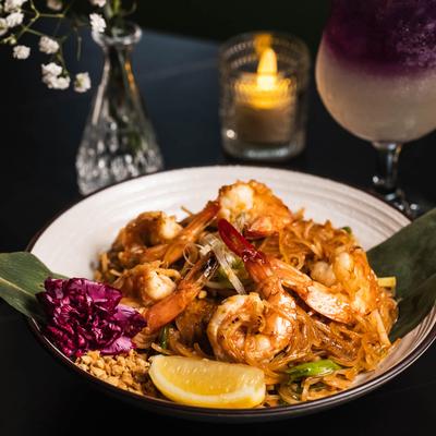 Shrimp pad Thai with rice noodles, crushed peanuts, and a lemon wedge.