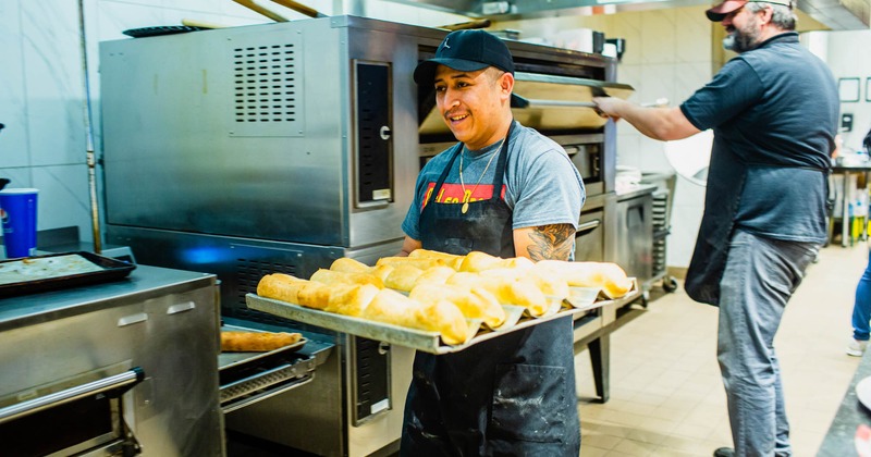 An employee holding a tray of baked bread