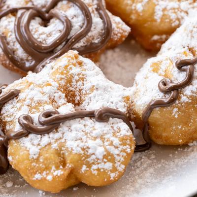 Fried vegan dough, with chocolate drizzle and powdered sugar.