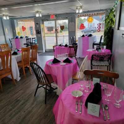 Set tables with pink tablecloths, glassware, silverware, and napkins.