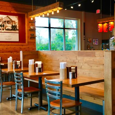 Interior with wood-paneled walls, booths, tables and chairs and red lanterns.
