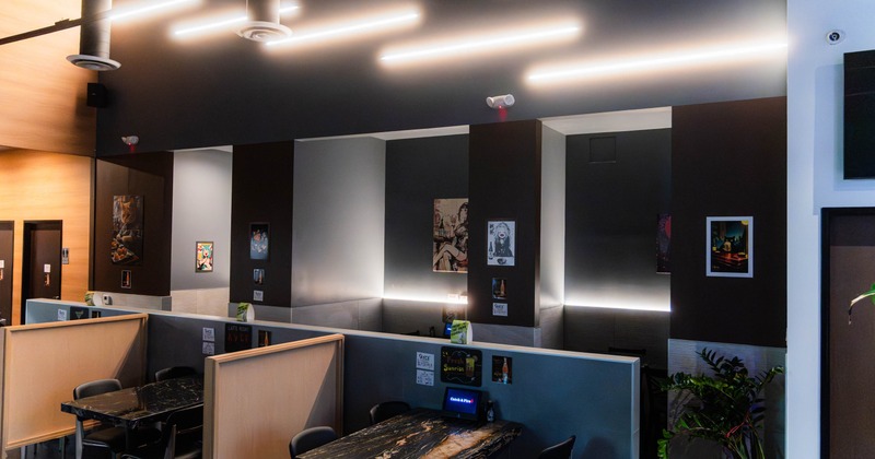 Interior - black chairs & marble tabletop, illuminated by linear light fixtures; dark and light wall