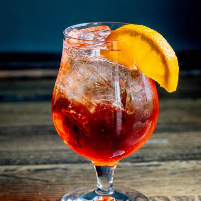 Aperol Spritz cocktail garnished with an orange slice on a table.