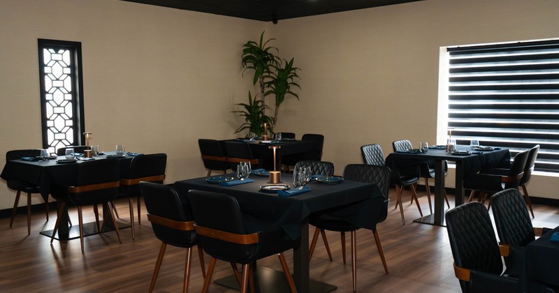 Modern restaurant interior with neatly arranged tables covered in black tablecloths