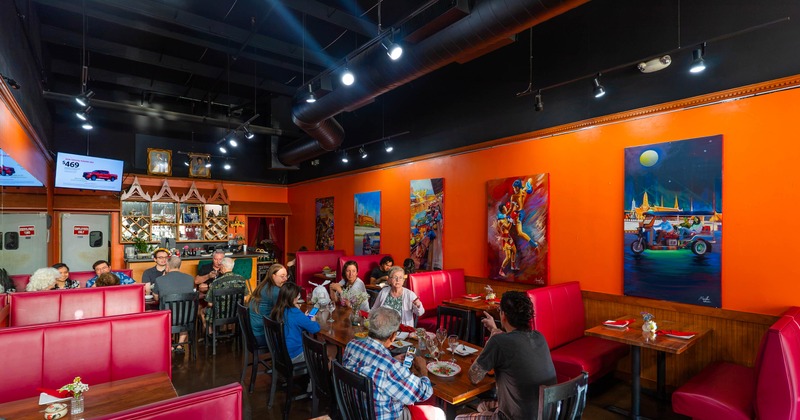 Dining area featuring vibrant orange walls adorned with large, colorful paintings