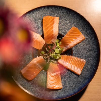 Seared salmon carpaccio with microgreens on a plate.