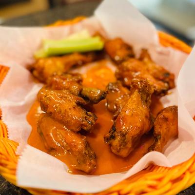 Buffalo chicken wings served with a side of celery on a paper-lined basket.