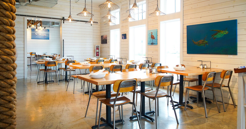 Interior, tables with tableware and seats, walls decorated with paintings of sea animals