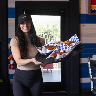 Server holding a tray with food baskets.