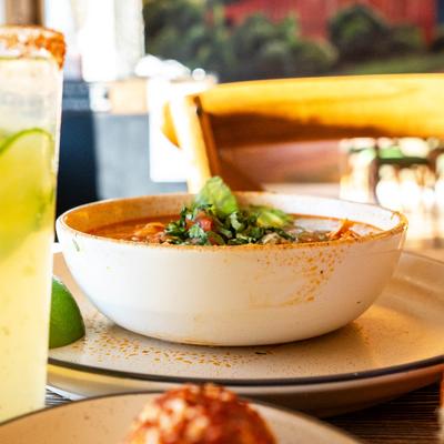 Chicken and rise soup served on the table with other dishes and drinks.