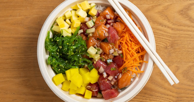 Poke bowl featuring diced raw tuna and salmon, wakame, diced mango and carrots