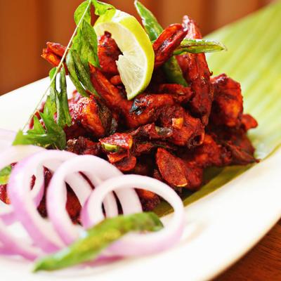 Curry leaf chicken served with red onions and a lemon wedge.