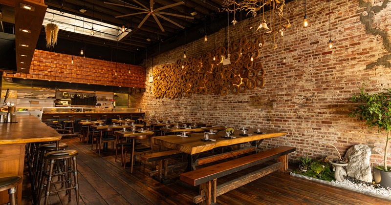 Warm restaurant interior with brick walls, wooden tables and bar, and ambient lighting