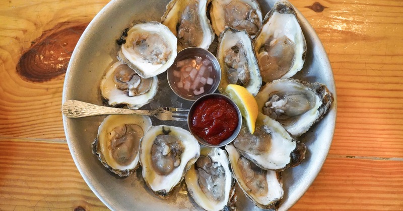 Oysters arranged around sauces on a metal platter