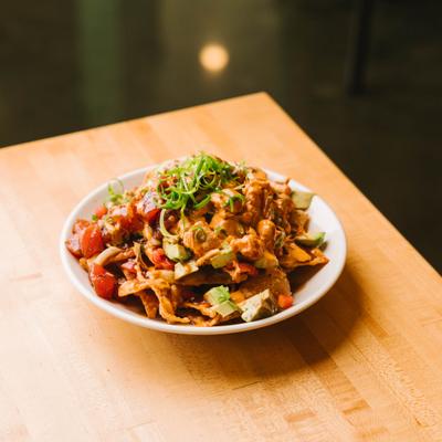 Poke nachos topped with sauce and herbs.