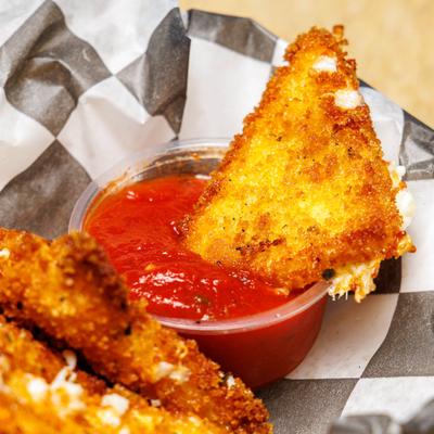 Fried Mozzarella served with marinara sauce, close-up.